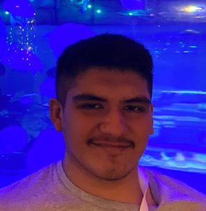 Young man smiling in front of a blue aquatic background